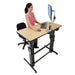 Ergotron WorkFit-D Sit-Stand Desk Birch with person standing in front of computer